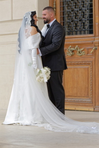 Couple in wedding attire posing in front of a wooden door